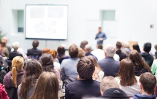 Speaker Giving a Talk at Business Meeting. Audience in the conference hall. Business and Entrepreneurship. Copy space on white board.